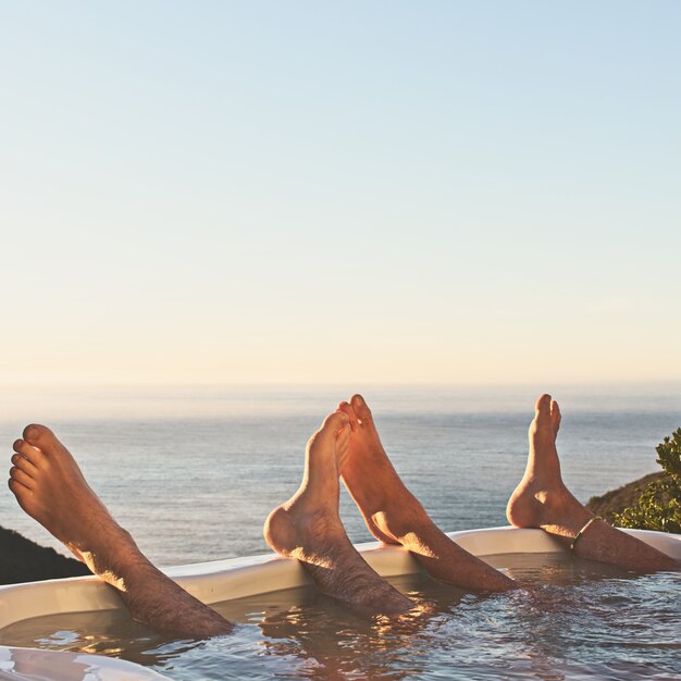 Bella vista di due persone con i piedi su una piscina con vista sull'oceano