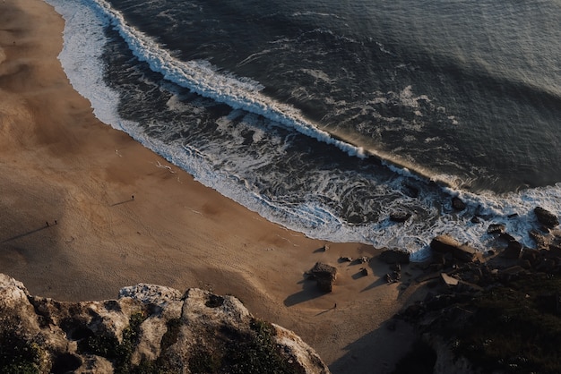 Bella vista di grandi onde che si infrangono su una spiaggia al tramonto