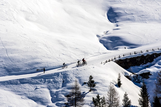 Bella vista di persone in bicicletta attraverso le montagne innevate in Alto Adige, Dolomiti, Italia