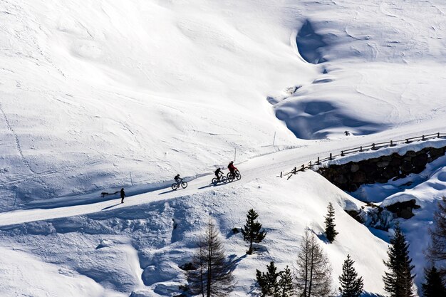 Bella vista di persone in bicicletta attraverso le montagne innevate in Alto Adige, Dolomiti, Italia