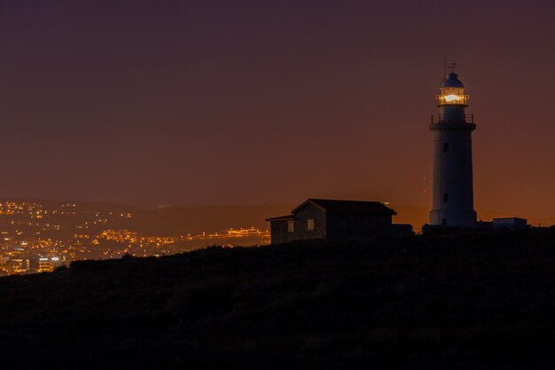 Bella vista di un faro e una casa su una collina catturata di notte a Cipro