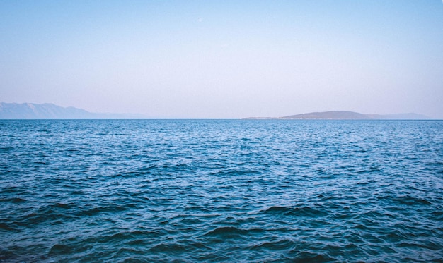 Bella vista di un mare blu con montagne sullo sfondo sotto un cielo limpido