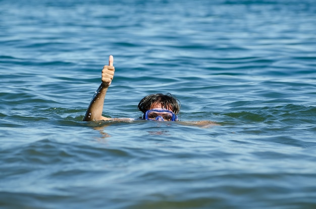 Bella vista di una donna che nuota nel lago con solo la testa e un braccio fuori dall'acqua