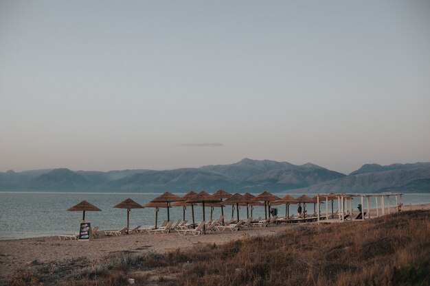 Bella vista di una spiaggia con sdraio sotto ombrelloni di paglia