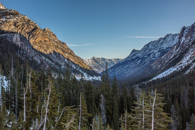 Bella vista su alte montagne rocciose e innevate e colline con una foresta