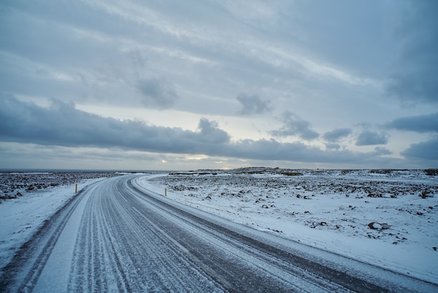 Bella vista sulla strada congelata vuota con ghiaccio in Islanda. oceano lontano, nuvole in cielo, brutto tempo invernale