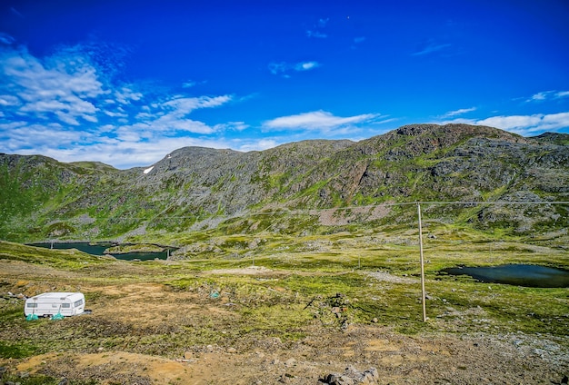 Bella vista sulle montagne coperte d'erba e sui campi sotto il cielo blu chiaro in Svezia