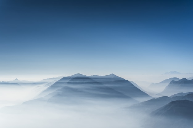 Belle colline coperte di nebbia e nuvole con cielo blu chiaro