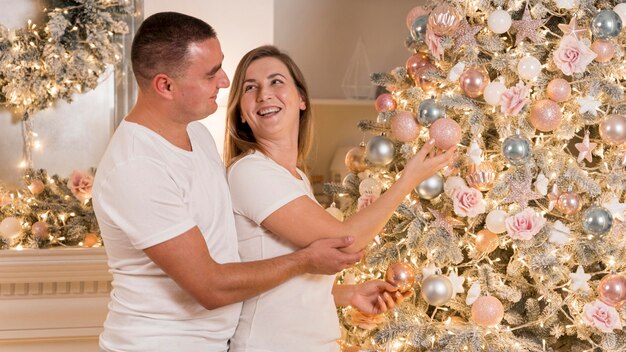 Belle coppie che decorano l'albero di Natale