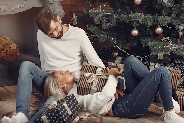 Belle coppie che si siedono a casa vicino all'albero di Natale