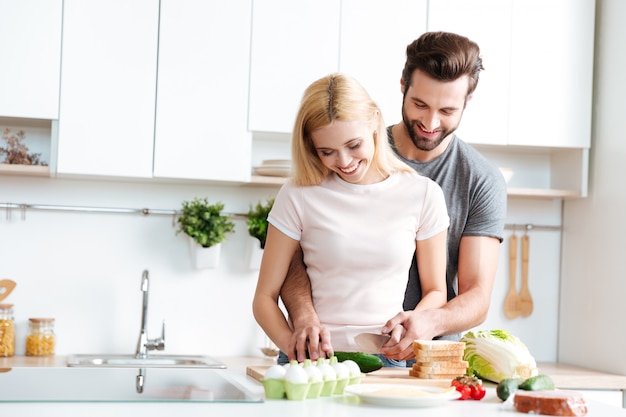 Belle coppie sorridenti che cucinano insieme in una cucina moderna