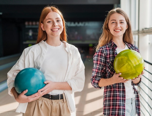 Belle donne che tengono le palle da bowling variopinte