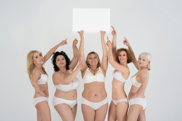 Belle donne di diverse forme e varie età in lingerie con segno bianco