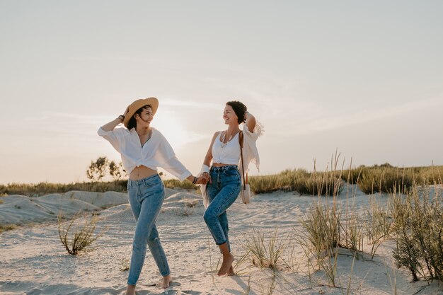 Belle due giovani donne che si divertono sulla spiaggia al tramonto, romanticismo gay amore lesbico