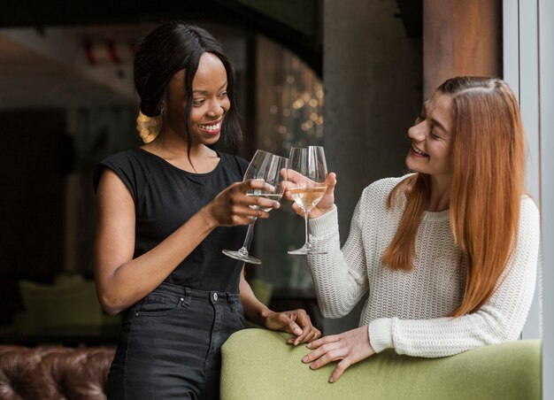 Belle giovani donne che tostano i bicchieri di vino