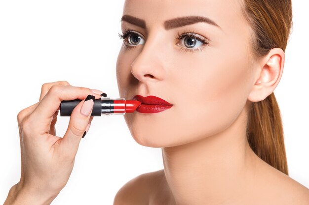Belle labbra femminili con trucco e pomata rossa su bianco. Processo di lavoro del truccatore