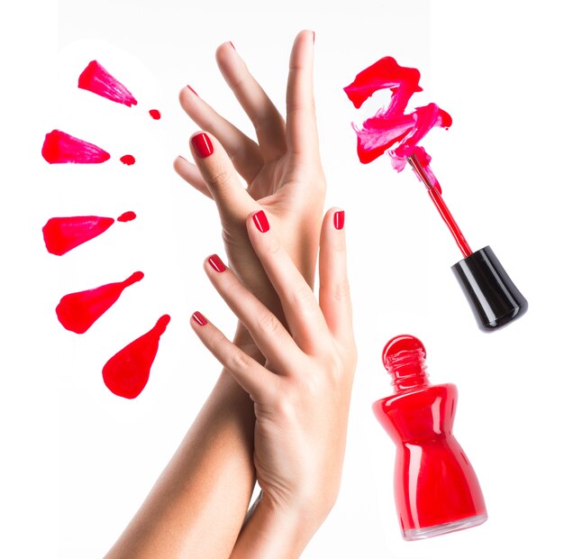 Belle mani femminili con manicure rossa e bottiglia di smalto con pennello