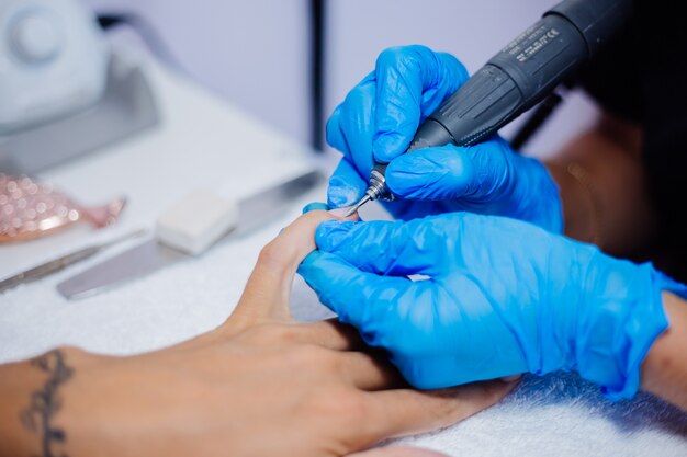 Belle mani femminili Processo di fabbricazione di trattamento delle unghie delle dita Trapano lima professionale per unghie in azione Concetto di cura delle mani e di bellezza