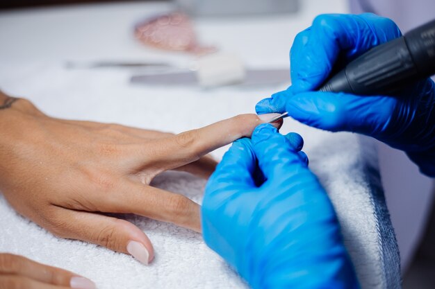 Belle mani femminili Processo di fabbricazione di trattamento delle unghie delle dita Trapano lima professionale per unghie in azione Concetto di cura delle mani e di bellezza