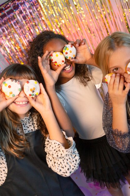 Belle ragazze alla festa festiva che tiene cupcakes