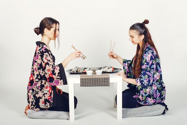 Belle ragazze che mangiano un sushi in uno studio