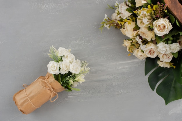 Belle rose bianche su scatola di legno e in bouquet su superficie grigia