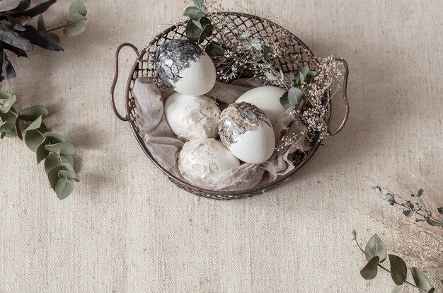Belle uova di Pasqua in un cesto decorato con fiori secchi. Felice Pasqua concetto.