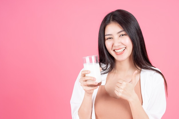 bellezza donna asiatica ragazza carina sentire felice bere latte per una buona salute al mattino su sfondo rosa
