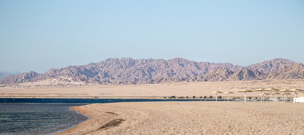 Bellissima spiaggia di sabbia deserta sullo sfondo delle montagne. Turismo selvaggio e concetto di viaggio.