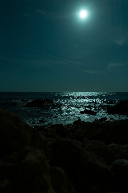 Bellissima spiaggia tropicale con la luna piena nei cieli notturni