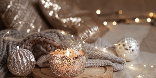 Bellissime decorazioni natalizie in argento lucido e candela accesa da vicino. Atmosfera invernale accogliente.