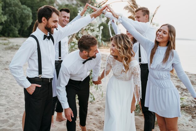 Bellissimi sposi che festeggiano il loro matrimonio con gli ospiti su una spiaggia