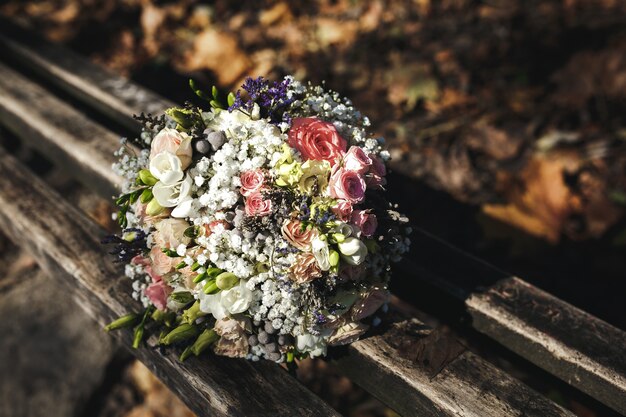 Bellissimo bouquet da sposa sdraiato su una panchina nel parco, matrimonio autunnale