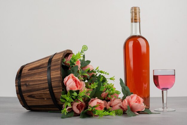 Bellissimo bouquet di fiori e una bottiglia di vino rosato sul tavolo grigio