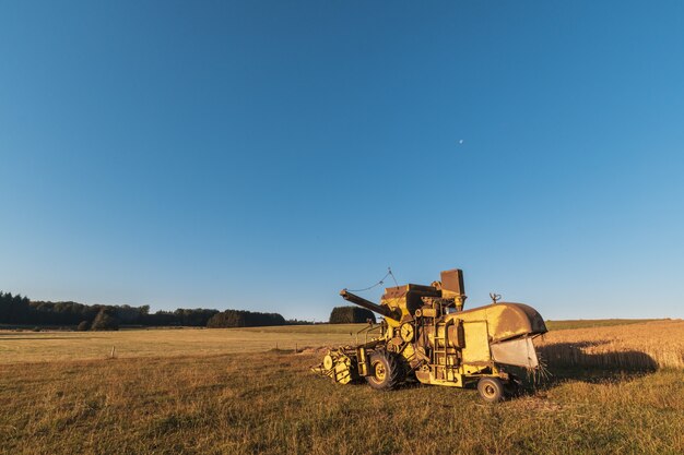 Bellissimo colpo di macchine mietitrebbia in fattoria con uno sfondo di cielo blu