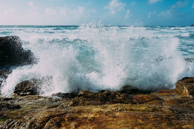 Bellissimo colpo di onde del mare che colpiscono grandi rocce vicino alla riva