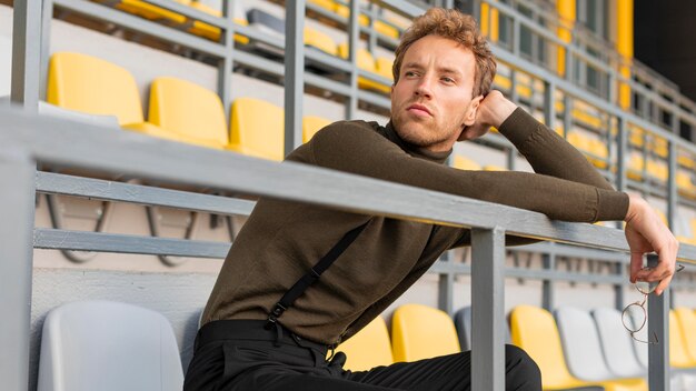 Bellissimo modello maschile seduto in uno stadio