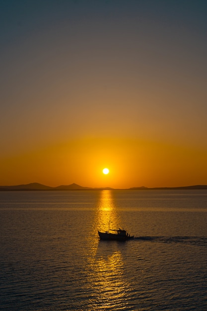 Bellissimo oceano con una piccola barca che galleggia sull'acqua al tramonto