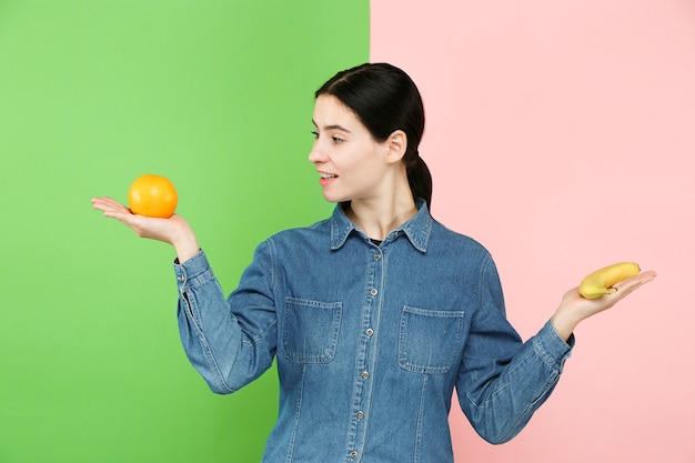 Bellissimo ritratto del primo piano di giovane donna con la frutta. Concetto di cibo sano. Cura della pelle e bellezza. Vitamine e minerali.