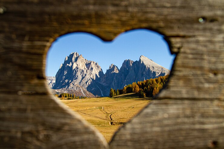 Foto gratuito bellissimo scatto da intere montagne e alberi verdi a forma di cuore in lontananza nelle dolomiti italia