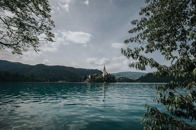 Bellissimo scatto del lago sanguinato da un edificio circondato da alberi in lontananza