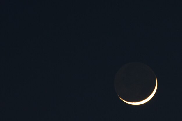 Bellissimo scatto del sole che va dietro la luna con un muro scuro