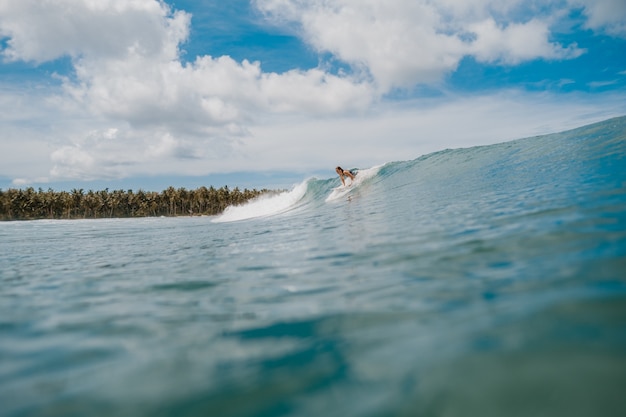 Bellissimo scatto dell'enorme onda che si infrange sul mare e del surfista in Indonesia