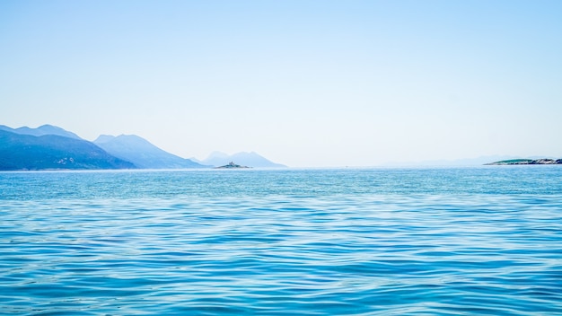 Bellissimo scatto di mare con una montagna in lontananza e un cielo limpido