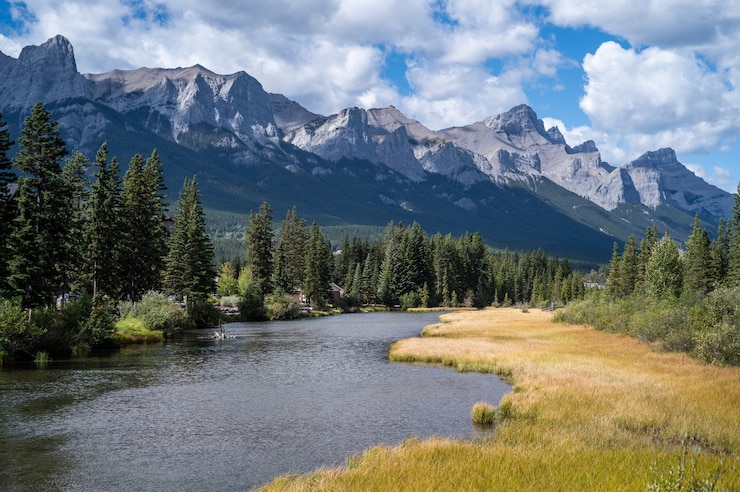Foto gratuito bellissimo scatto di un fiume attraverso il villaggio circondato da colline, montagne e verde