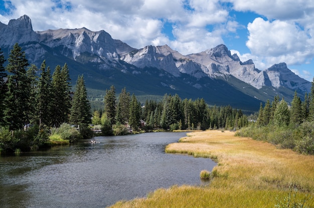 Bellissimo scatto di un fiume attraverso il villaggio circondato da colline, montagne e verde