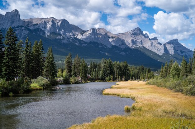 Bellissimo scatto di un fiume attraverso il villaggio circondato da colline, montagne e verde