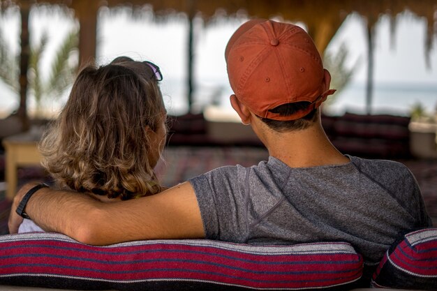 Bellissimo scatto di una coppia di innamorati in vacanza seduti su un divano e guardando il mare