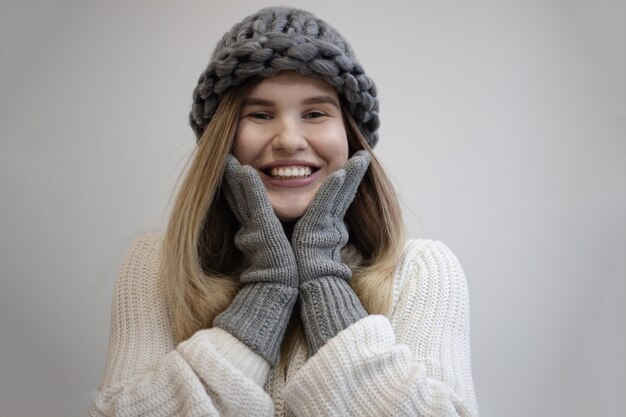 Bellissimo scatto di una donna piuttosto allegra che indossa guanti e cappello grigio lavorato a maglia