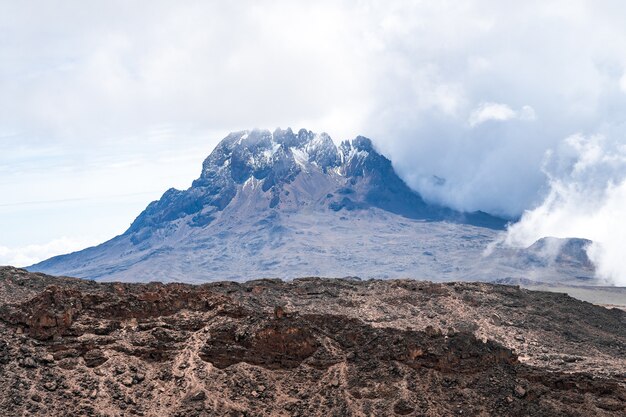 Bellissimo scatto di una montagna con le nuvole che creano un'atmosfera nebbiosa